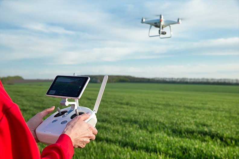 Drohnensteuerung mit einer Drohne im Hindergrund