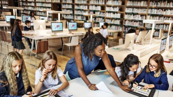 Klassenzimmer mit vielen Kindern und PCs und Tablets