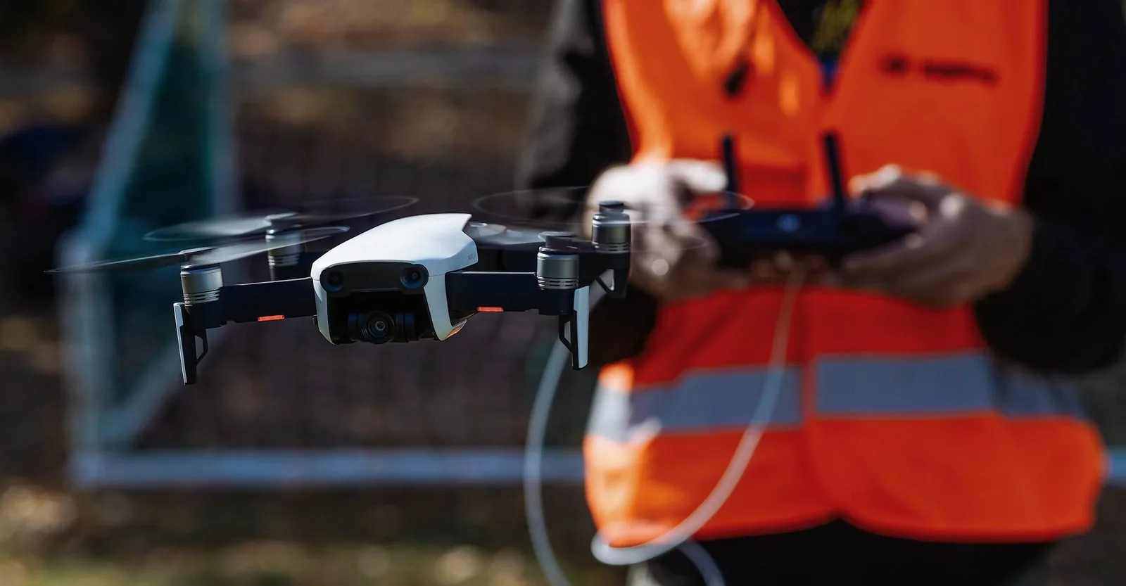 Two participants in hi-vis vests flying drones at a training ground