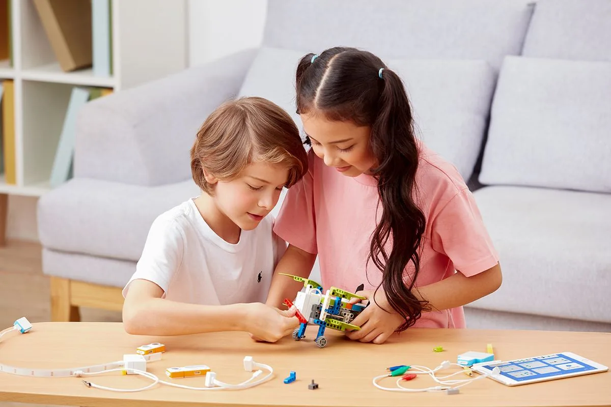 Two children building an educational robot from a kit