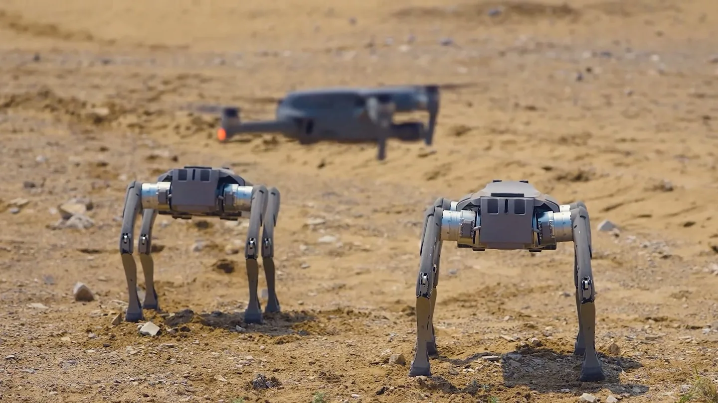 Two legged robots and a drone on a joint mission in open terrain