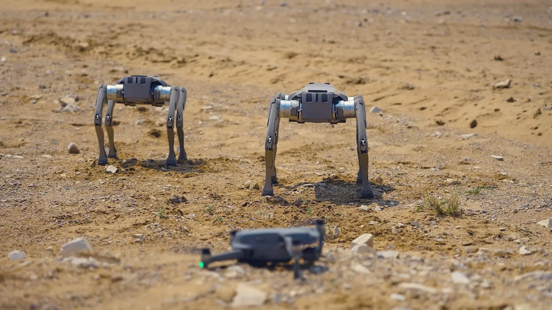 Two legged robots and a drone on a joint mission in open terrain