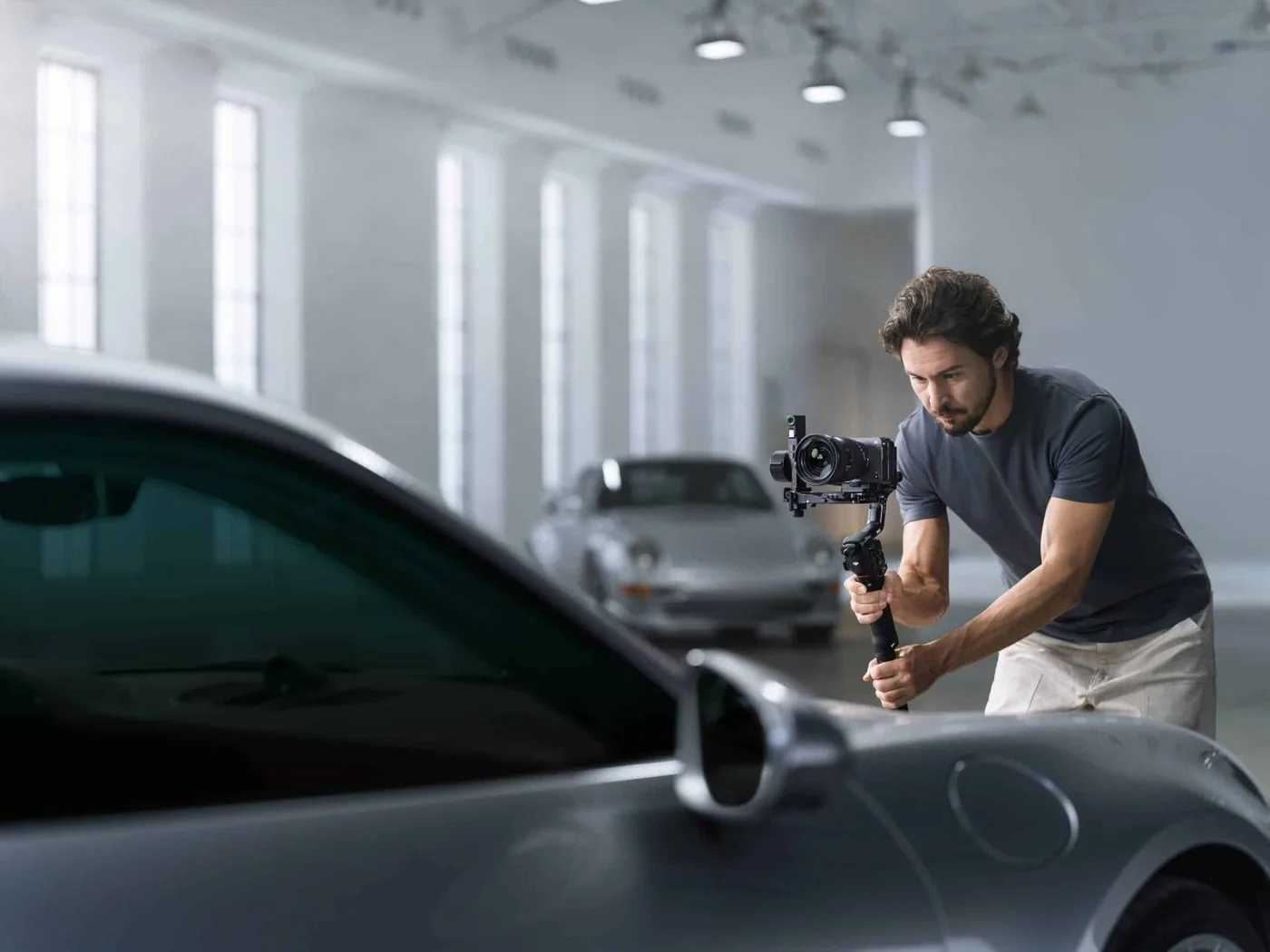 Camera operator filming a sports car in a hall with a DJI RS gimbal