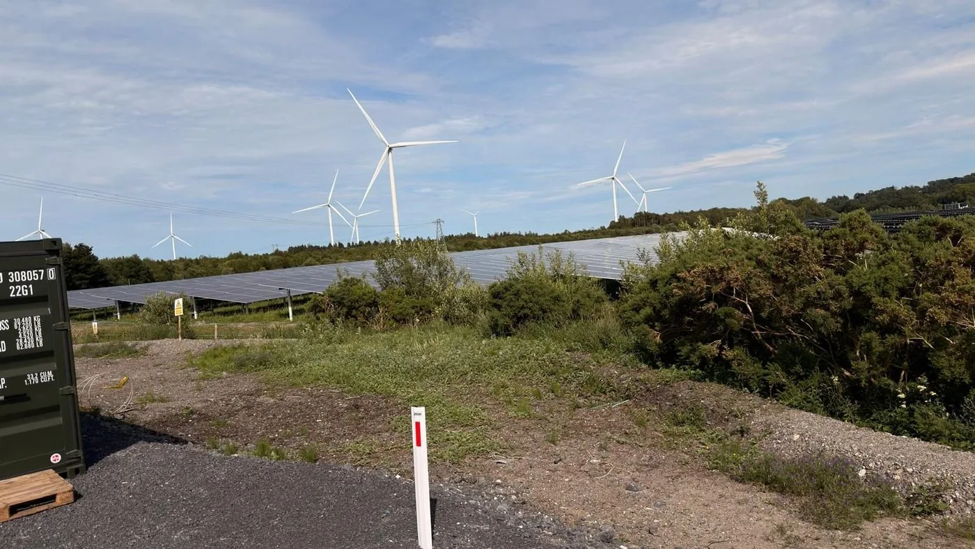 Solar farm site with wind turbines in the background