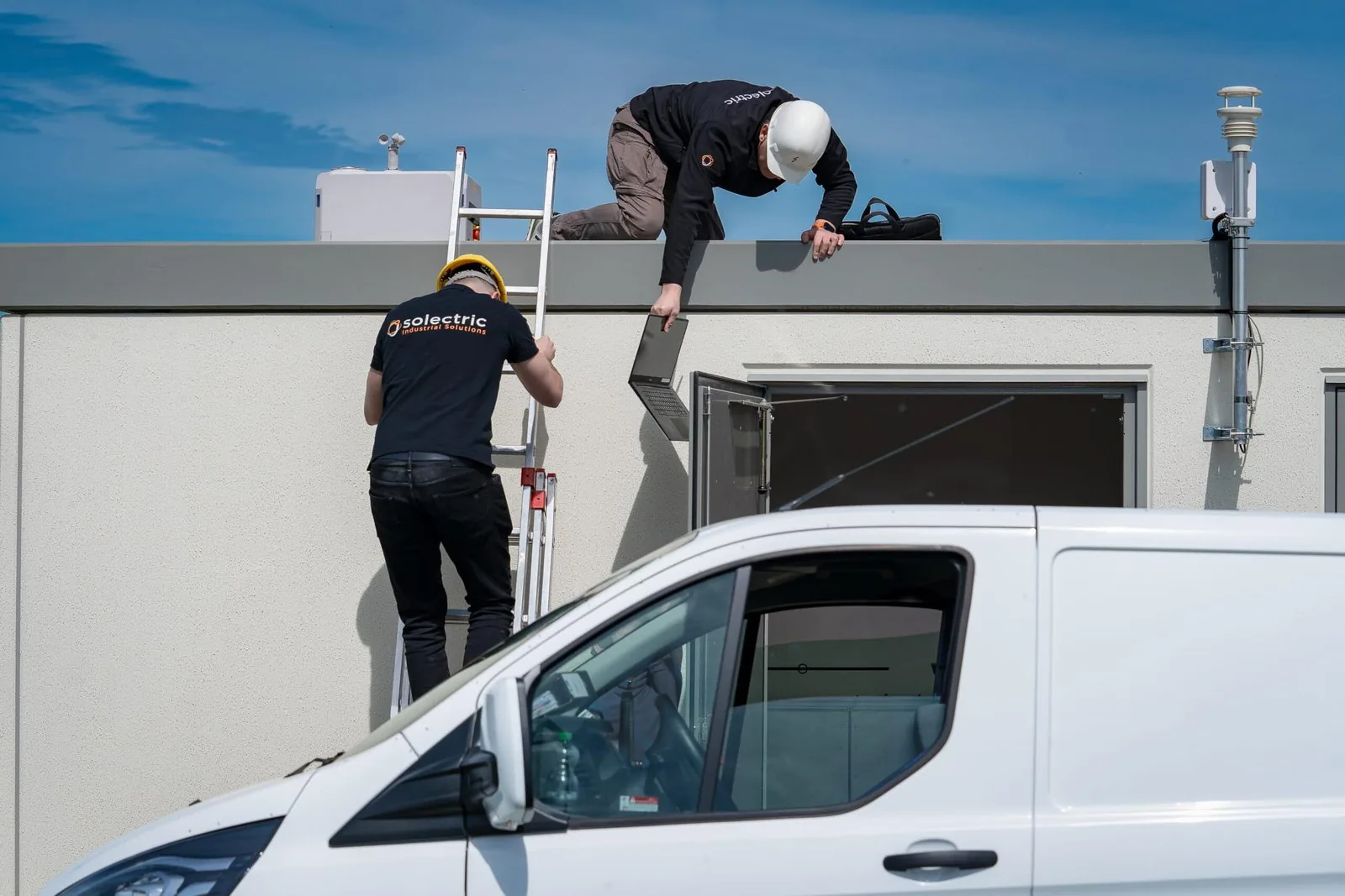 Two Solectric technicians installing a drone dock on a roof