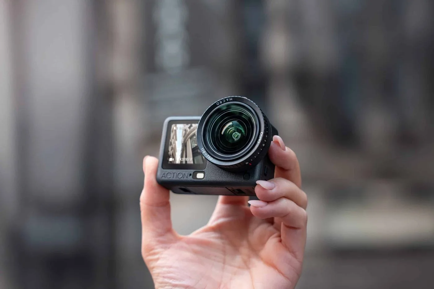 Camera with a macro lens attached, held in one hand
