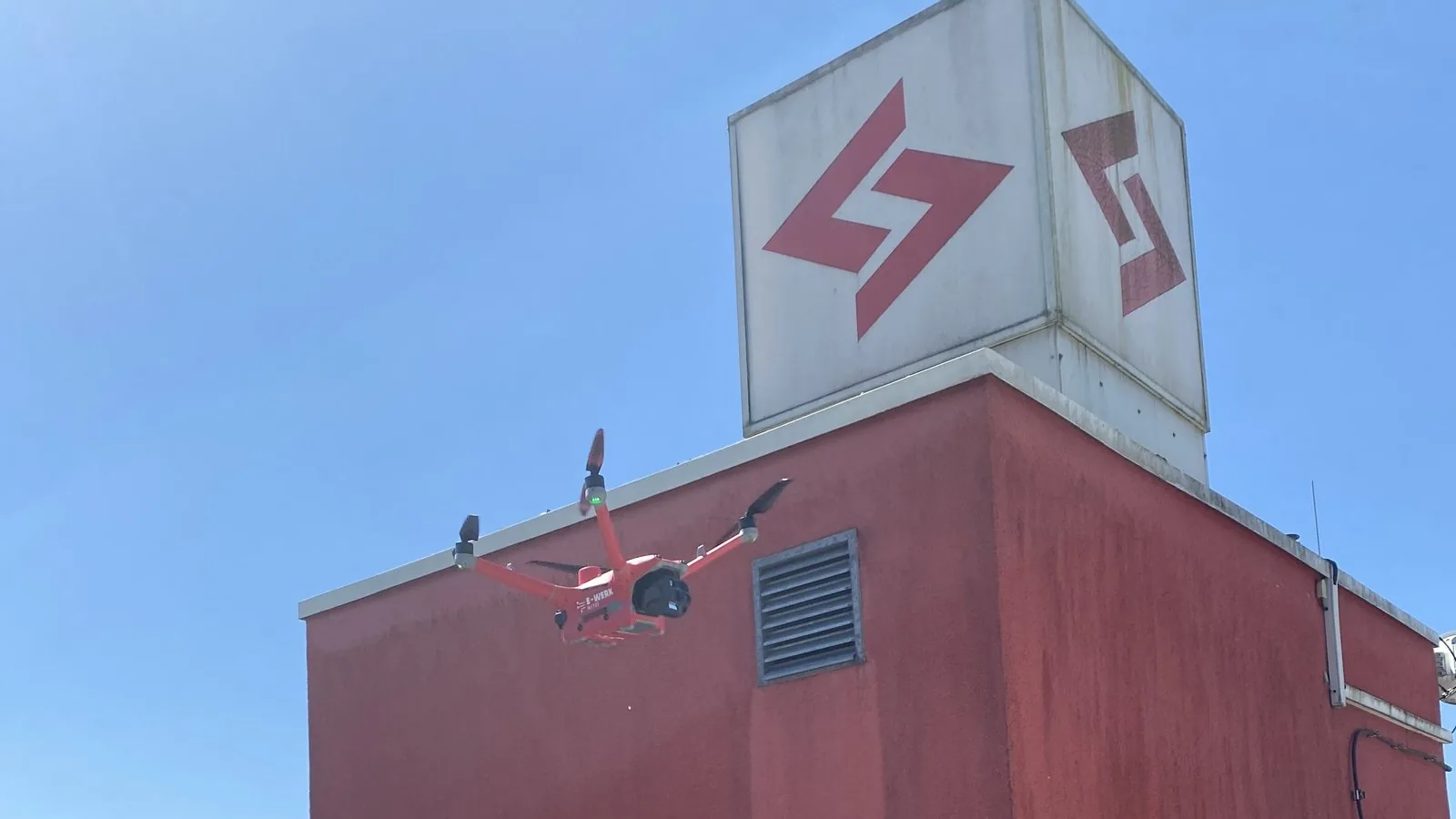 Red E-Werk Mittelbaden drone flying in front of the operations building with the E-Werk logo