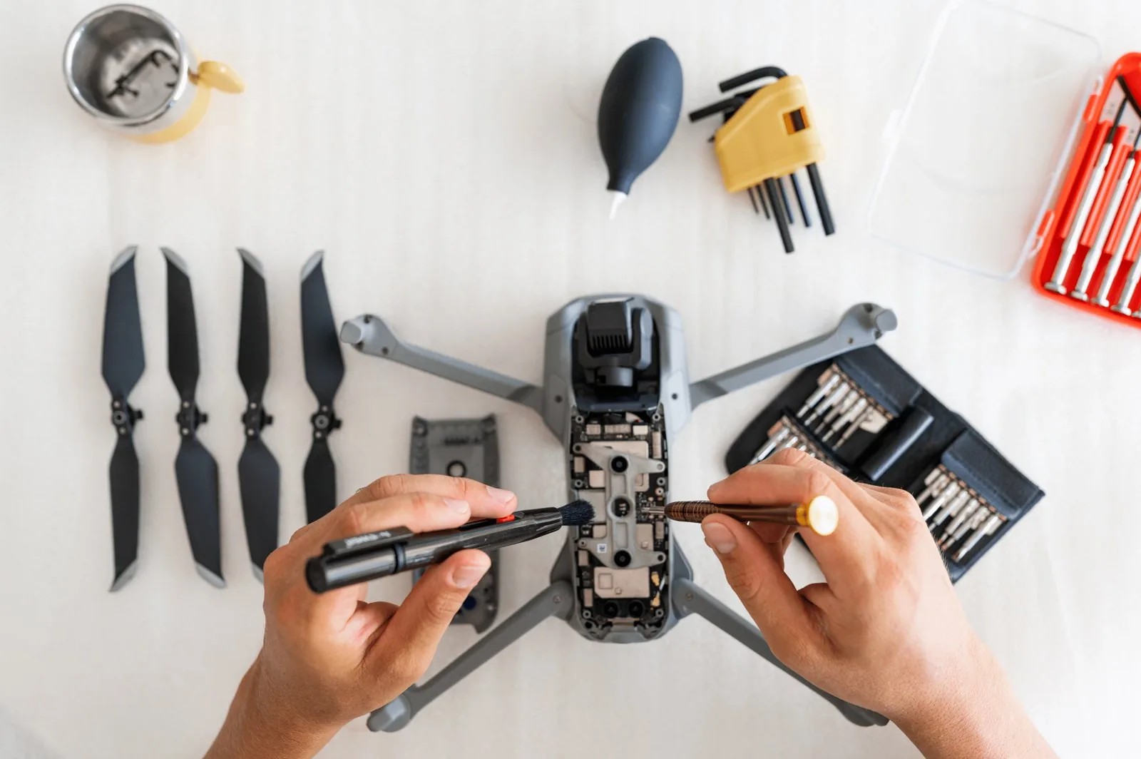 Dismantled drone on the workbench, with propellers and a tool kit beside it
