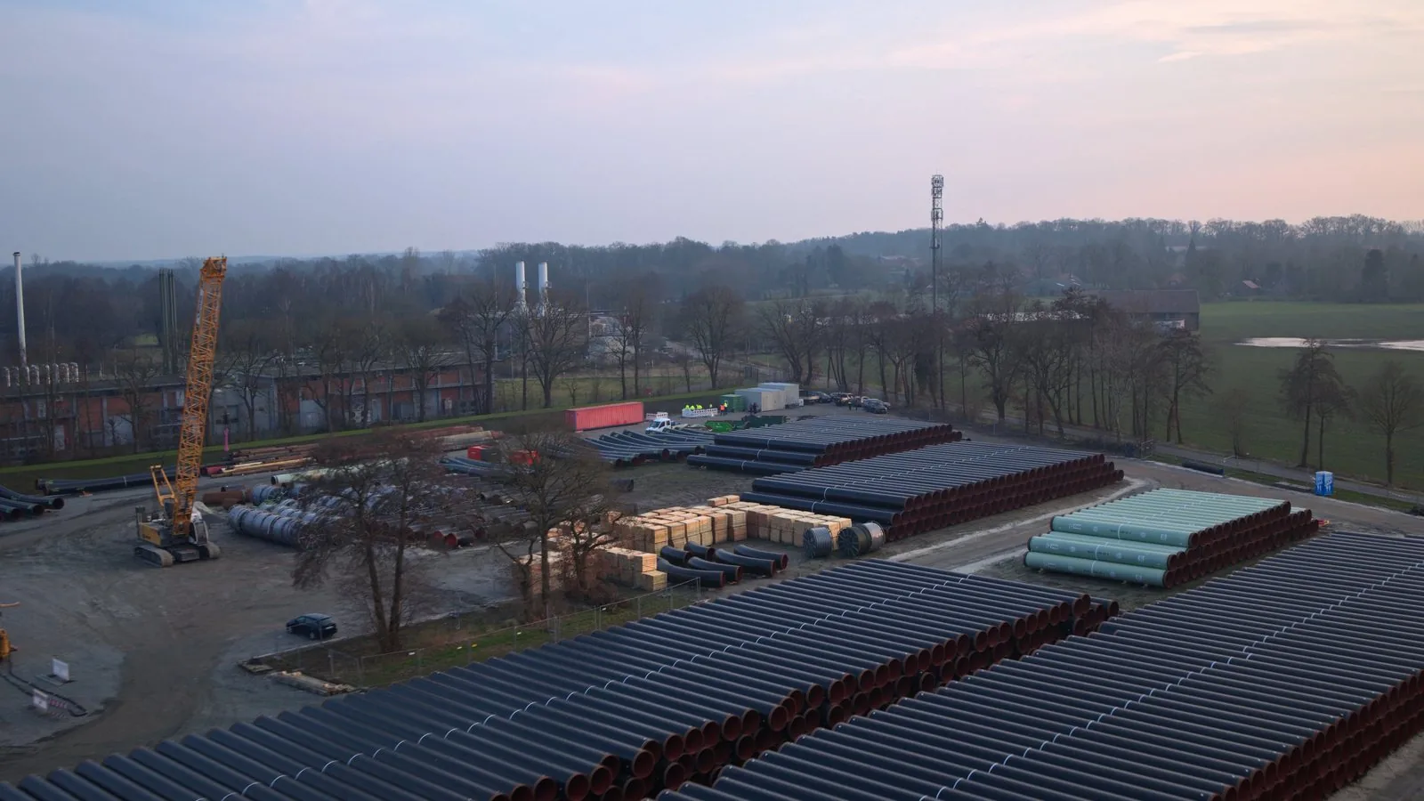 Aerial view of a site with a pipe yard, crane and buildings